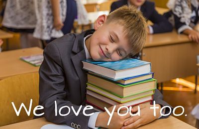 text reads 'we love you too' over an image of a young boy in a suit sitting at a desk,  laying his head on a stack of books, smiling.